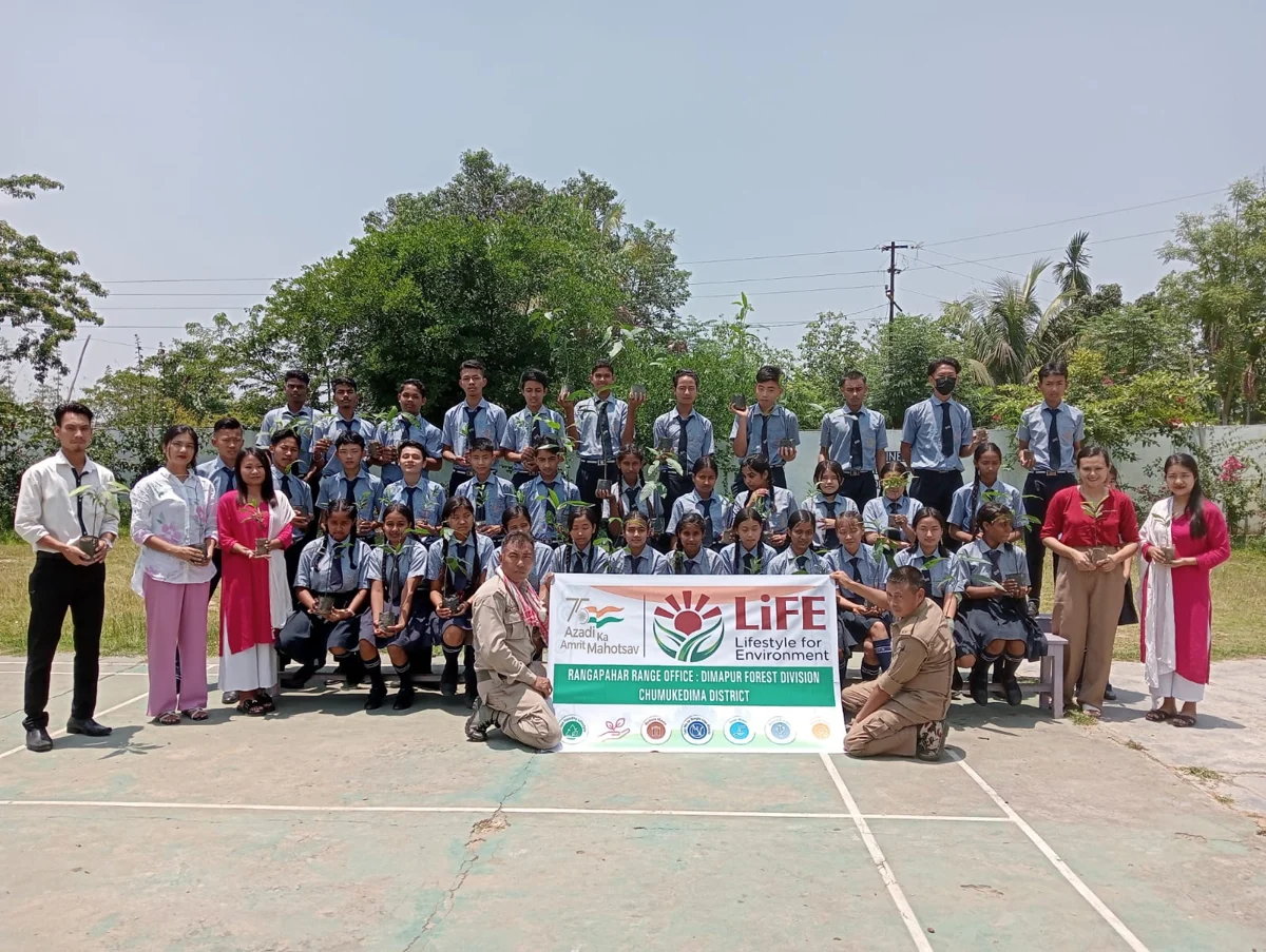 Students and staff holding saplings beside a Lifestyle for Environment banner