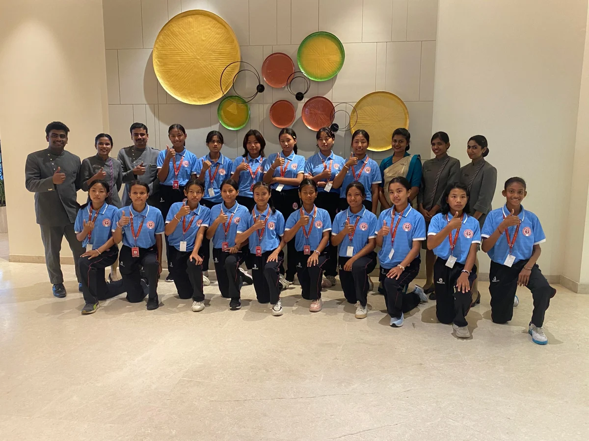 A women’s team in matching blue shirts posing with accompanying adults